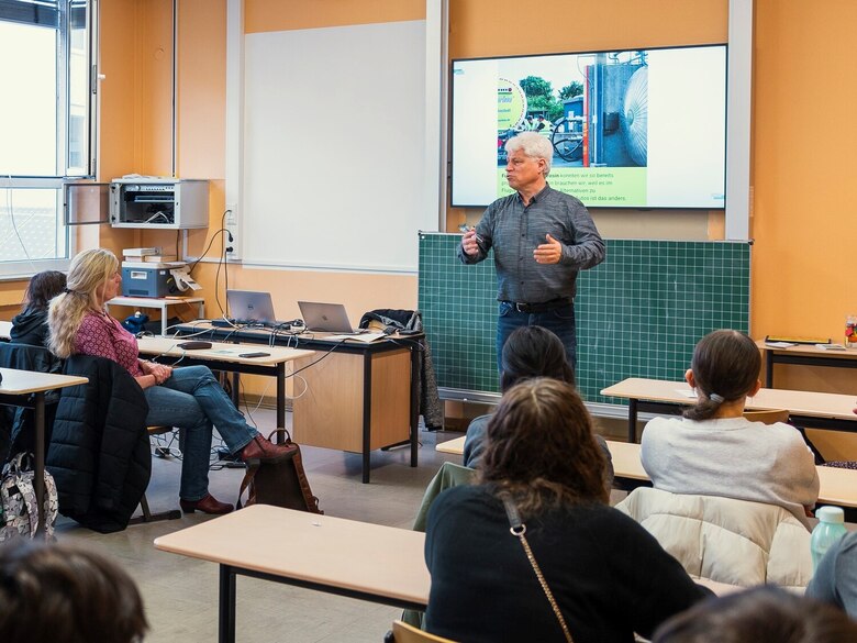 Herr Voigt steht vor einer Schulklasse. Im Hintergrund sieht man ein Satellitenfoto