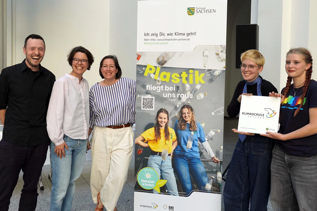 Schülerinnen und Schüler sowie Lehrkräfte des Gymnasiums Dresden-Johannstadt werden vor einem Klimaschulaufsteller fotografiert.