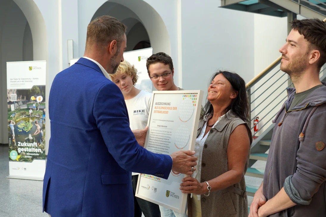 Patrick Schreiber, Präsident des Landesamtes für Schule und Bildung überreicht einer ausgezeichneten Klimaschule die Urkunde. .