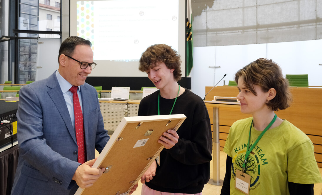 Minister Panter überreicht eine Urkunde an einen Schüler einer ausgezeichneten Klimaschule