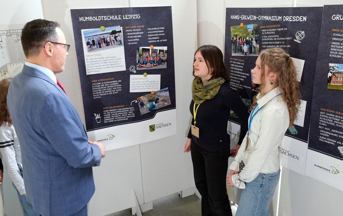 Minister Panter im Gespräch mit zwei Schülerinnen der Humboldtschule Leipzig vor ihrem Plakat