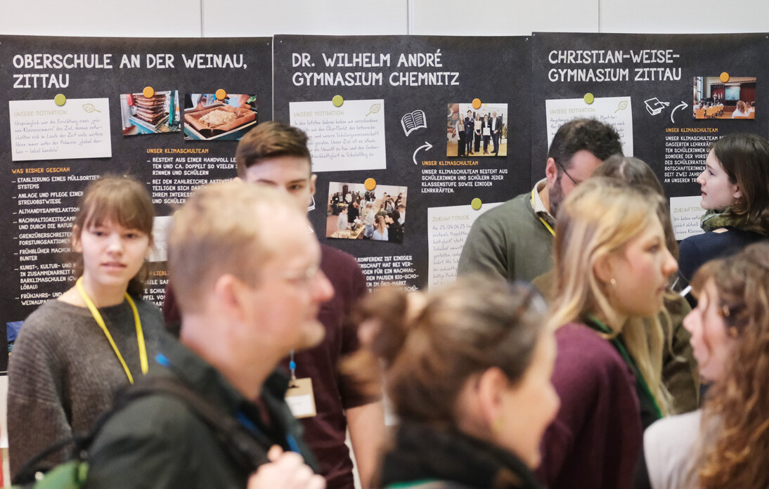 Teilnehmende der Klimaschulkonferenz vor den Plakaten der Klimaschulen